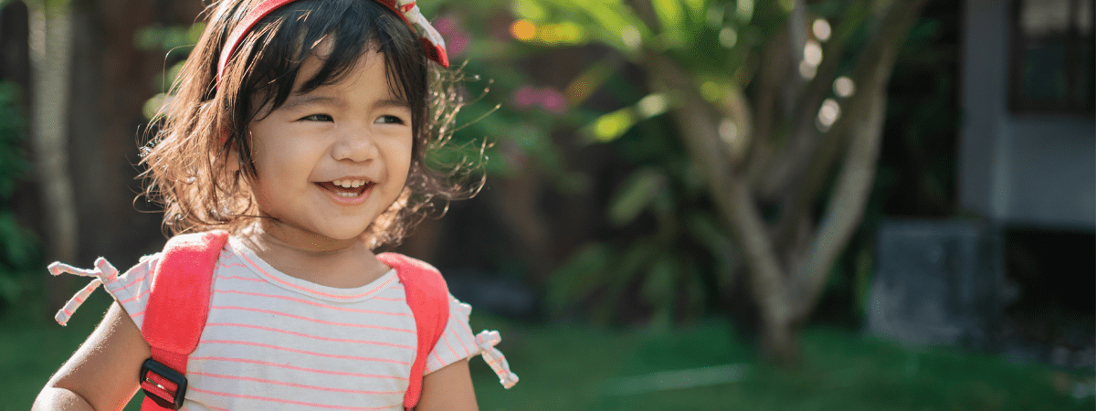 toddler in the outdoors carrying her backpack