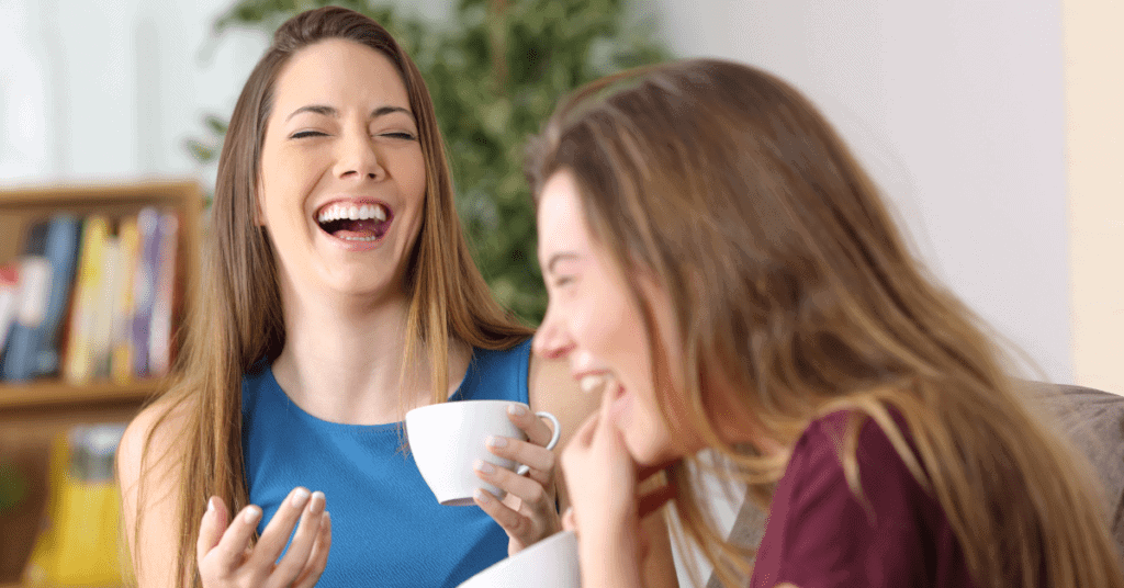 Two friends together laughing over coffee