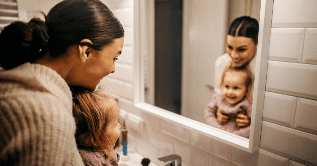 Mother and child smiling in the mirror and demonstrating body positivity
