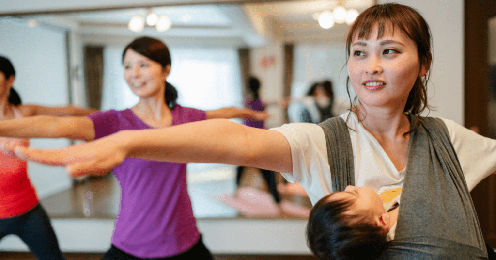 Mother at a Mum/Baby & toddler yoga group, with her baby in a sling