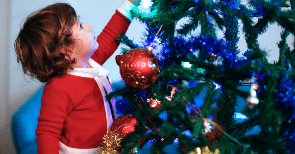 Christmas as a single parent: Image shows a toddler hanging a bauble on a Christmas tree