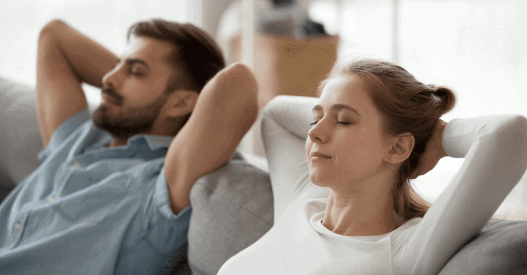 a mum and dad following our new year's resolutions idea of taking a moment to breathe, by sitting back and relaxing on their couch.