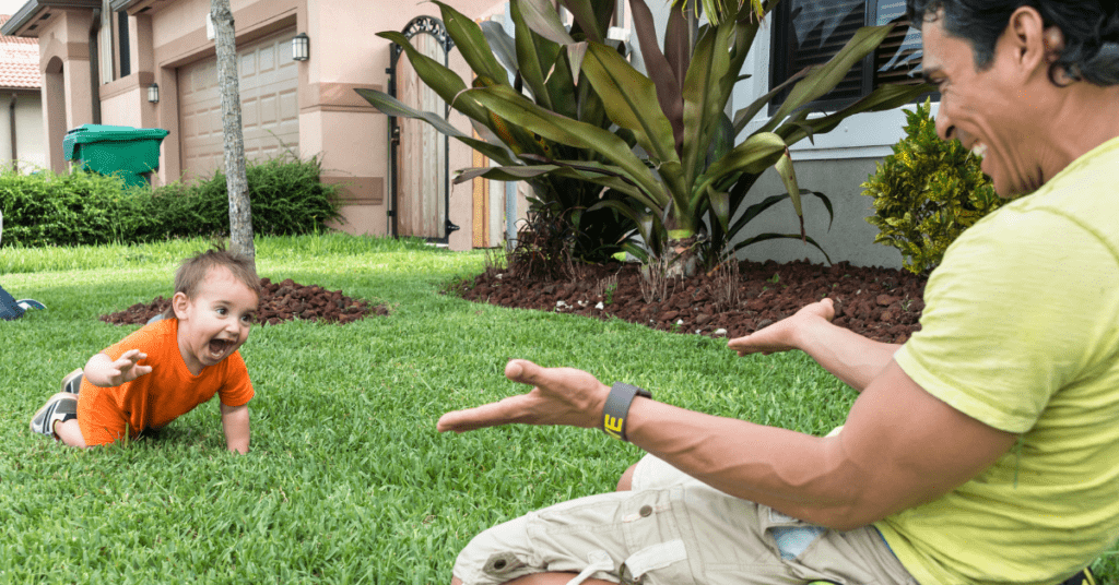 Dad excitably encouraging young baby to start crawling