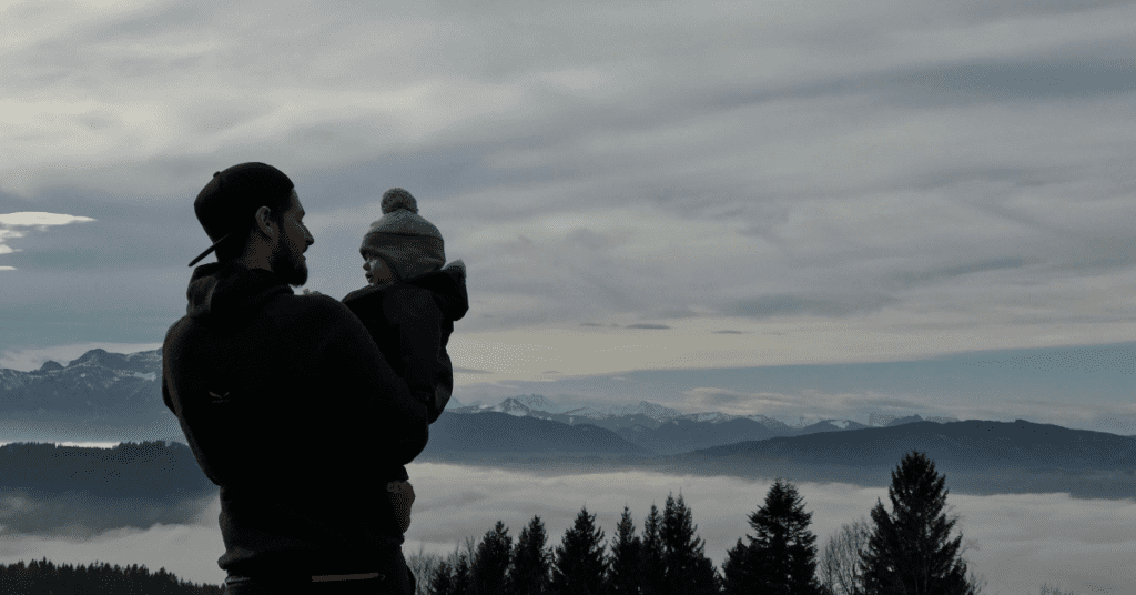 Dad's and loneliness, an isolated looking image of a father and his child out in nature looking over mountains.