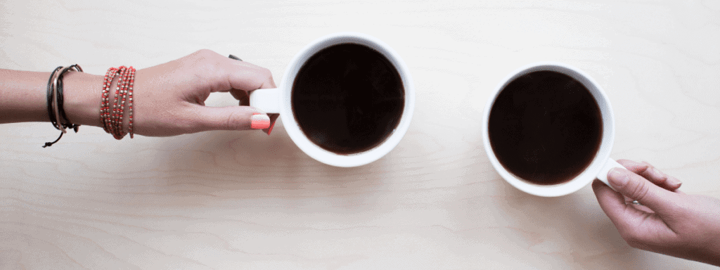 two women's hands holding cups of coffee