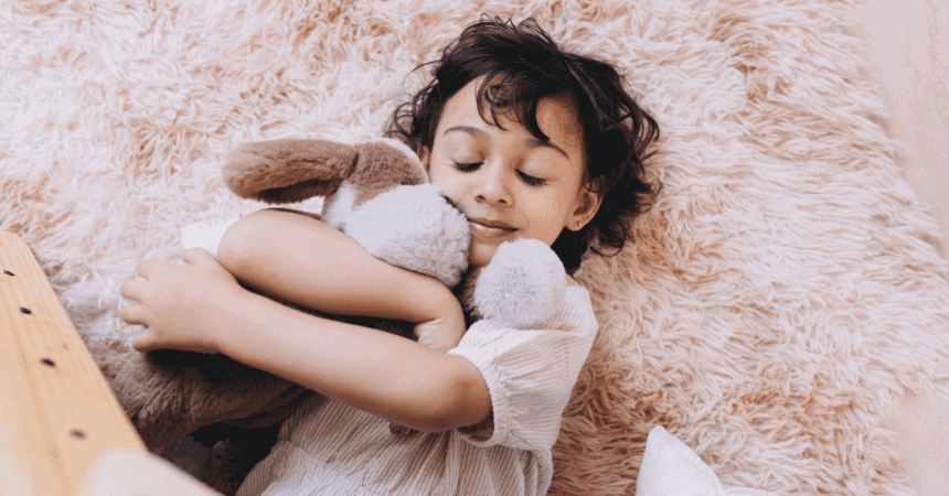 Young toddler cuddles with a stuffed toy while laying on a fluffy carpet