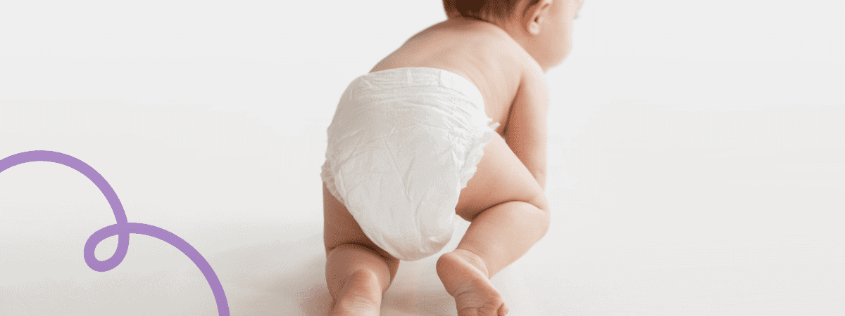 A baby crawls across a blank background, primarily wearing a nappy. 