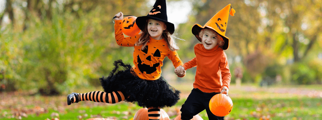 Two young kids running around happily in their halloween outfits, attending a spooky event
