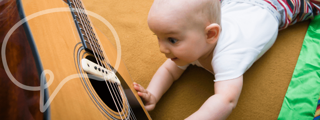 Copyright for baby and toddler classes: The image shows a baby looking at a guitar in awe