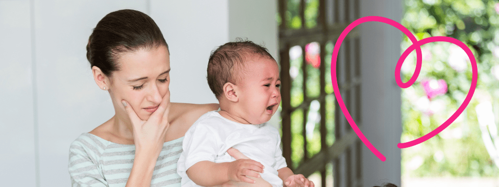 Mother looks disgruntled holding a crying baby. 