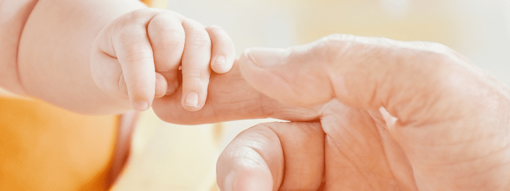 The 5 senses for a baby: to demonstrate touch, this image shows a baby hand holding an adult's forefinger.