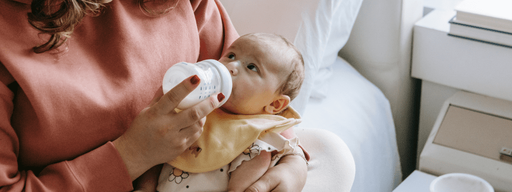 To demonstrate taste , this image shows a baby looking up to their mother while bottle-feeding