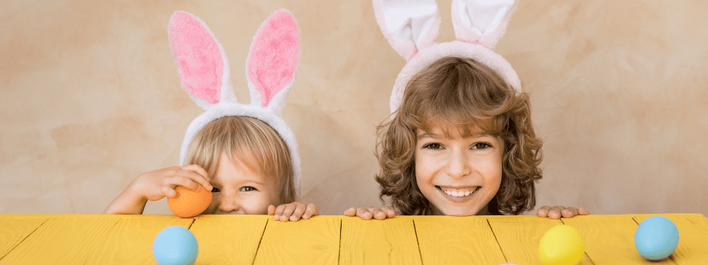 Easter Activities Toddlers: Two kids stand peeking over a table wearing bunny ears