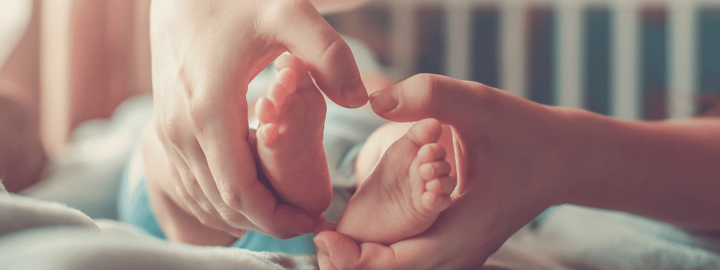 Anxiety as a new mum -image shows newborn feet and hands holding a heart around them. 