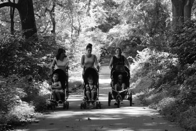 Image depicts a group of mums pushing toddlers in a pram. Support group for maternal mental health