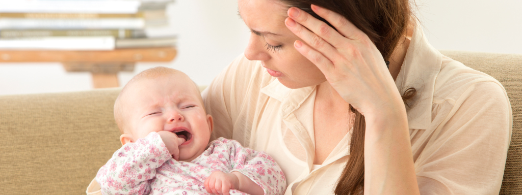Baby holds at their mouth crying, suggesting that they're experiencing teething pains. 