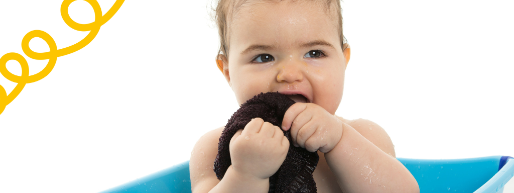 Baby teething tips - Image shows a baby gently gumming on a wet flannel