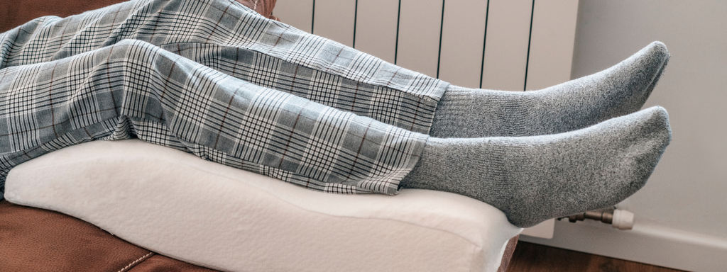 image shows a pair of legs elevated by a footrest/cushion.