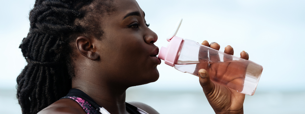 image shows a woman drinking from a water bottle. 