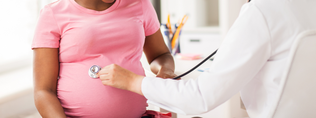 leg cramps during pregnancy - image shows a doctor holding a stethoscope to a pregnant woman's baby bump. 