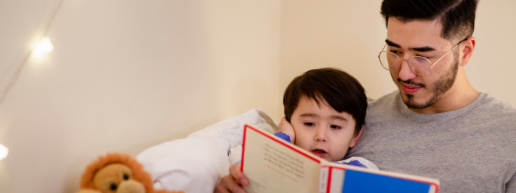 autism and sleep in children - image shows a father telling their son a bedtime story.