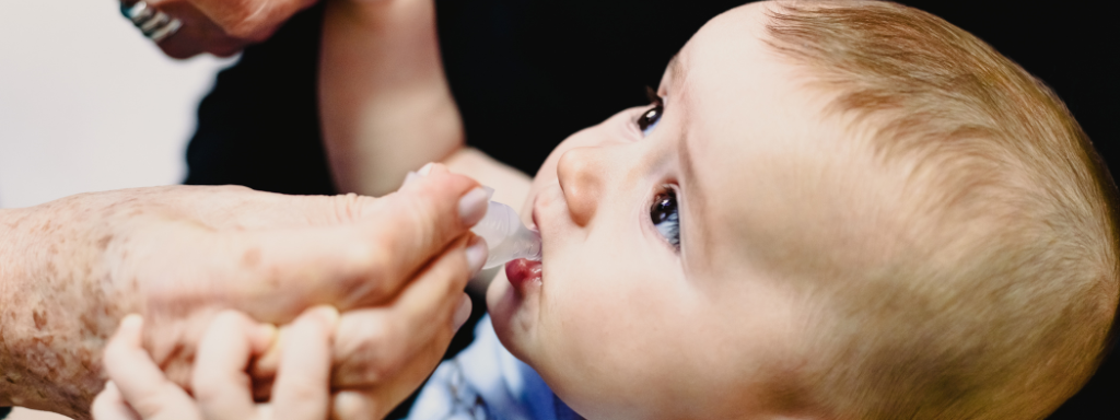 Baby's first cold - image shows baby receiving medicine through a small pipet
