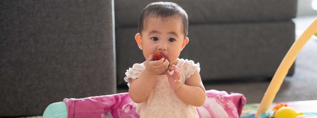 baby weaning - image shows a baby eating a strawberry