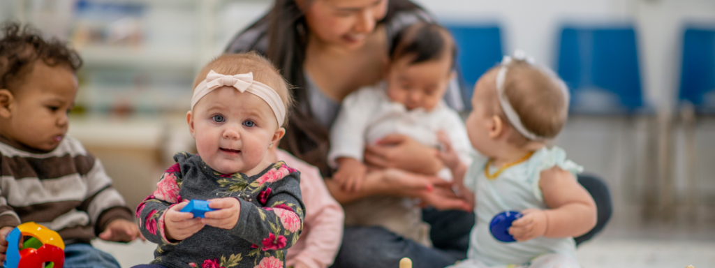 Going back to work after parental leave  - Image shows a childcare environment, where a woman sits with a number of babies.