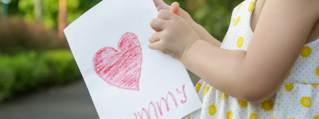 Image shows a toddler holding a card that says 'mummy'