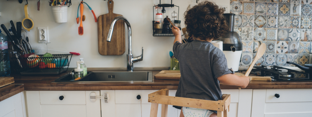 Developmental Activities With Your Toddler - image shows a toddler playing in the kitchen