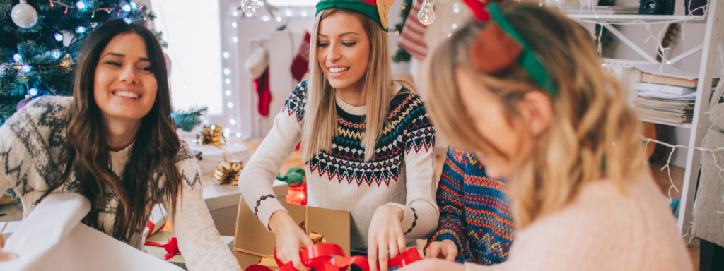 Christmas as a single parent - image shows a mother with two daughter (one teenager and one child) wrapping Christmas presents together.