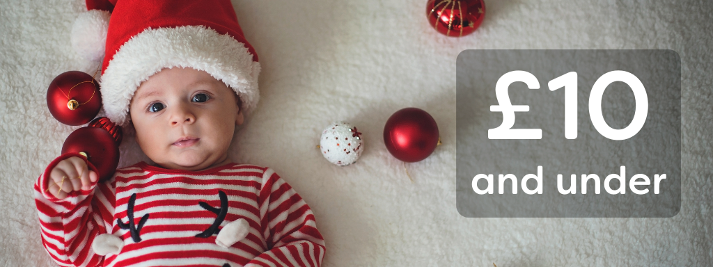 baby stocking fillers £10 and under - image shows a baby laying on a carpet surrounded by Christmas baubles