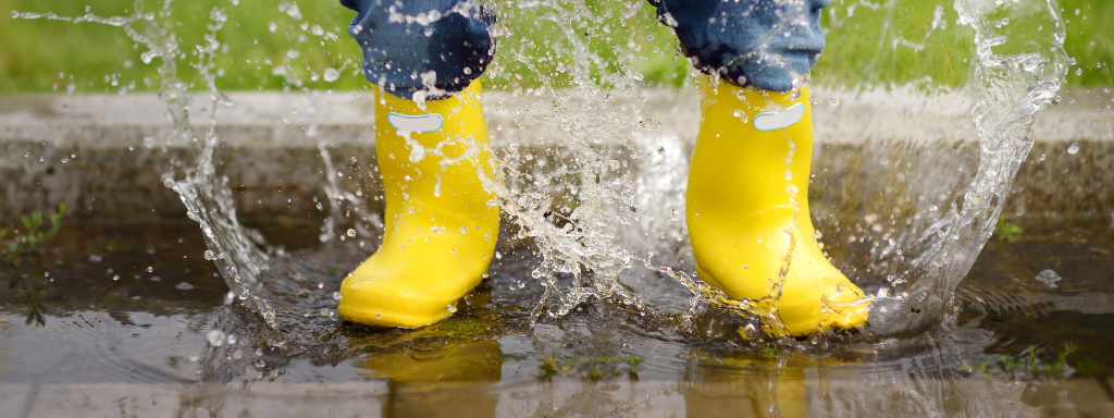 Outdoor clothing for babies - image shows a toddler in wellies splashing in a puddle