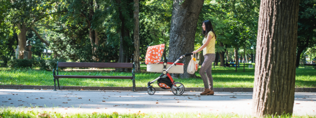 de-stress as a parent - image shows a woman pushing a buggy through a park