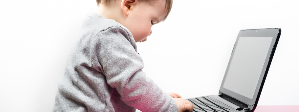 image shows a baby typing on a computer