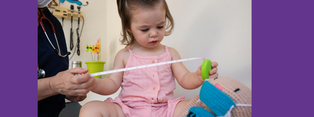 A toddler looks at a measuring tape