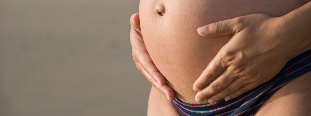 A lady puts hers hands on her pregnant belly