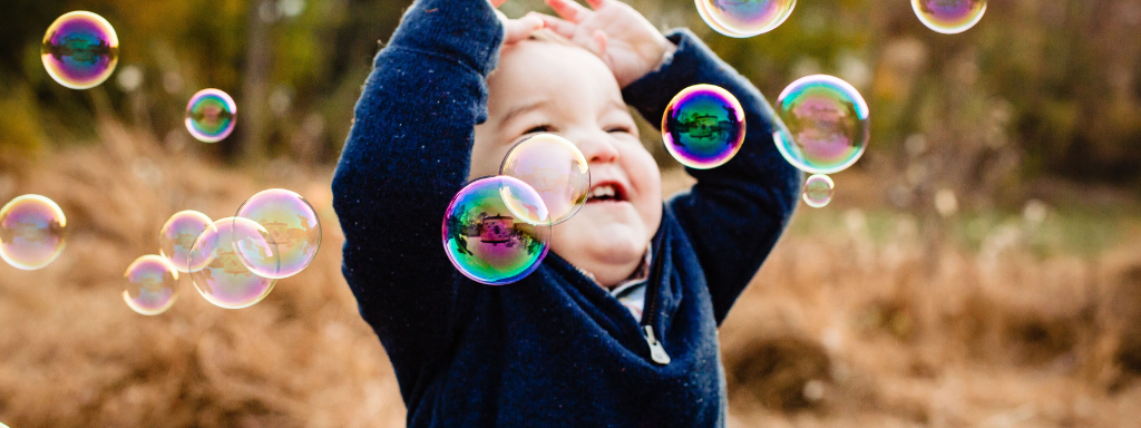 stimulating play ideas babies - image shows smiling and being surrounded by bubbles