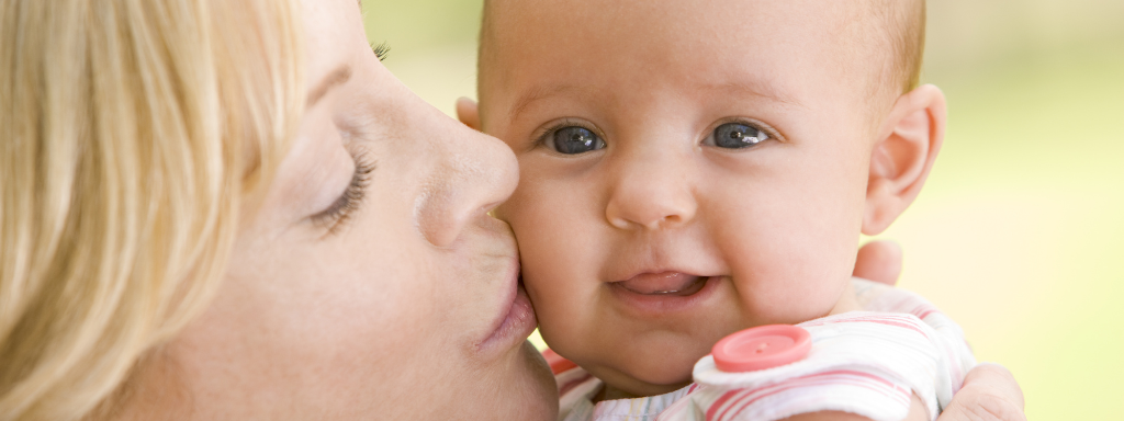 image shows a baby being kissed by their mother.