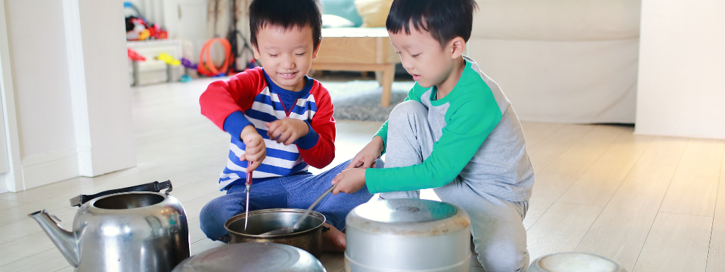 Two children play in the kitchen hitting pans