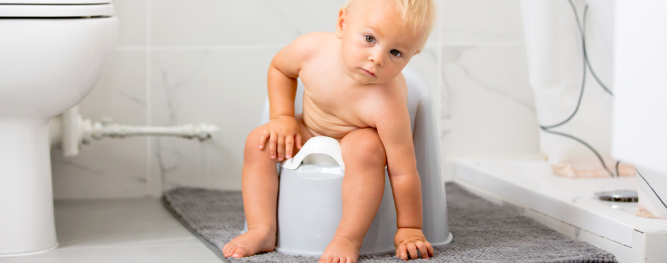 A toddler sits on a potty