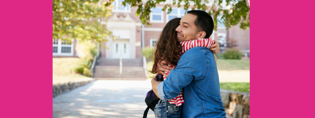 A dad hugs his daughter outside a school