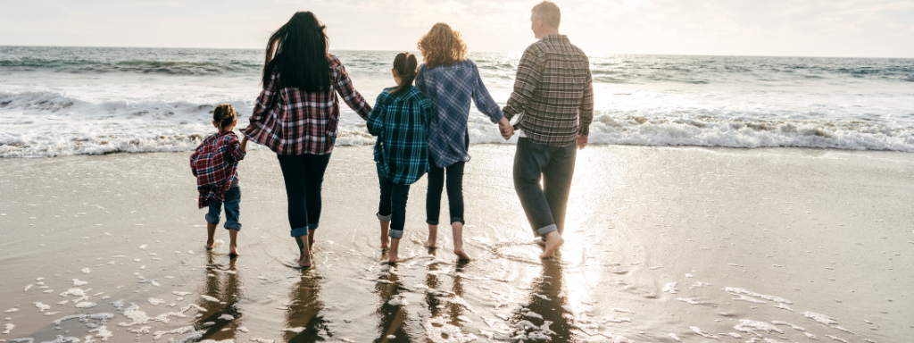 A family hold hands, while paddling in the sea