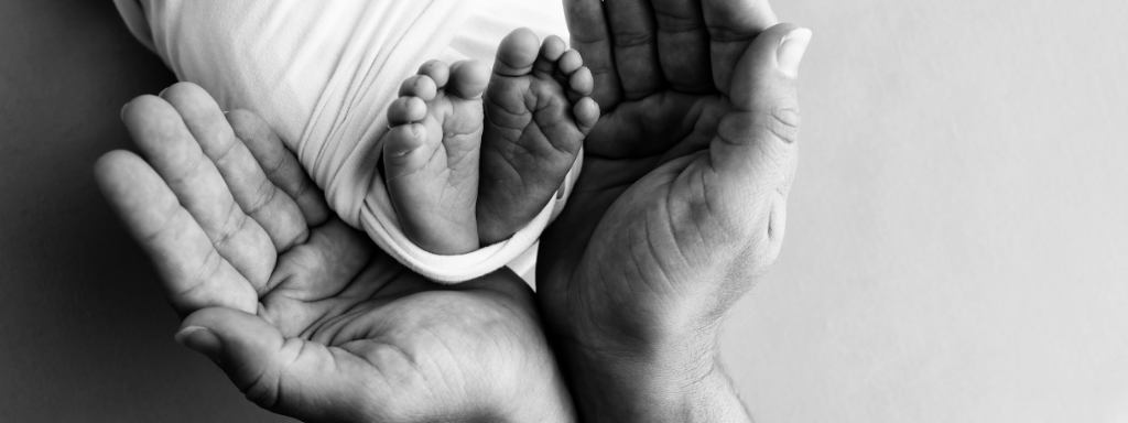 Tiny baby feet are cradled in an adult's hands