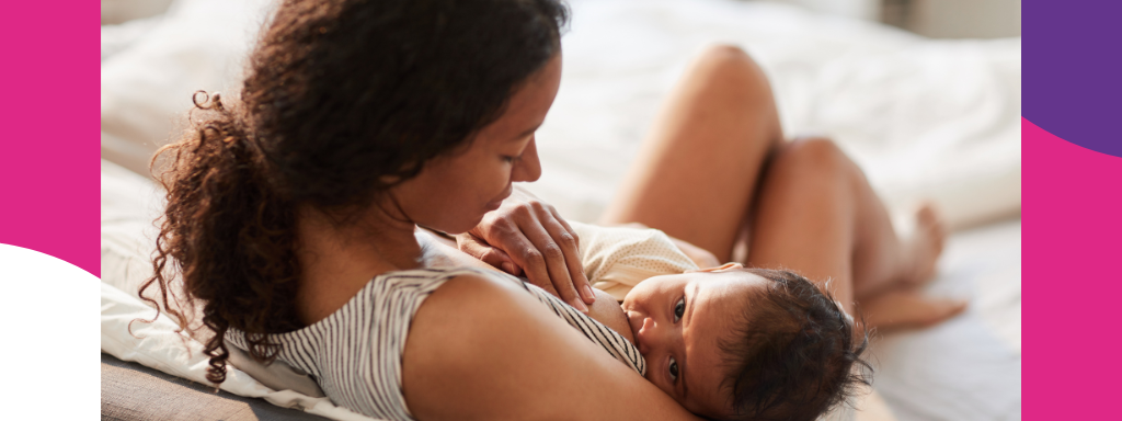 A mum feeds her baby, sitting on a bed