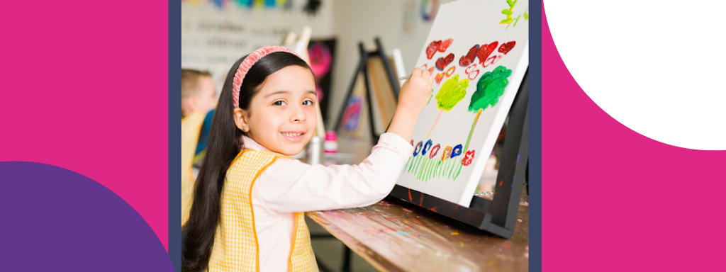 A child smiles in front of an easel 