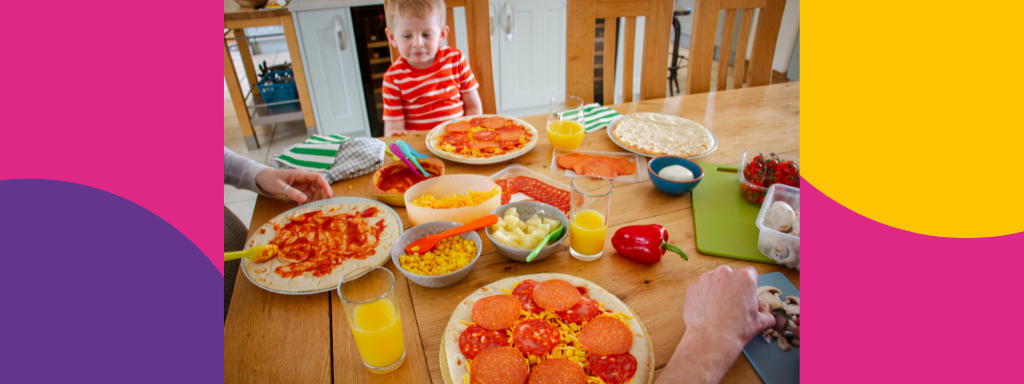 A toddler adds toppings to a pizza