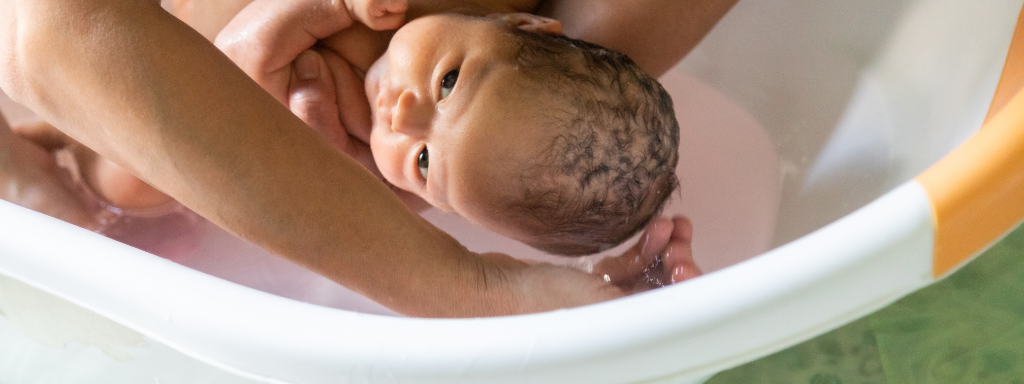 baby shower gifts - the photograph shows a baby being bathed in a baby bath