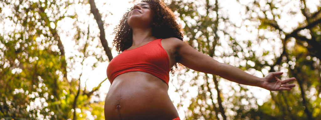 pregnancy brain - the photograph shows a pregnant woman in a forest with her arms in the air, looking happy to be in nature